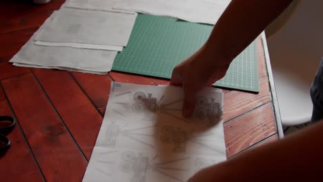 placing two pieces of fabric of equal size on top of eachother on a cutting board with other fabric squares. slow motion.