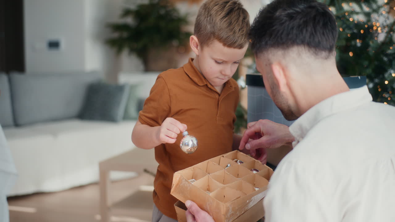 niño y su padre preparan decoraciones de navidad y decoran el árbol de navidad