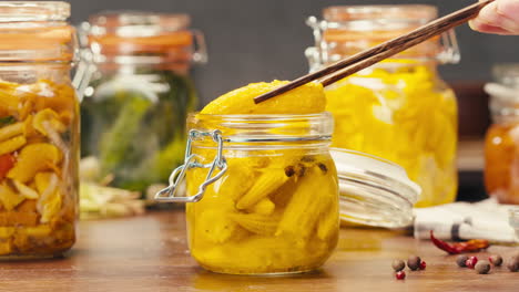 fermented food in glass cans on table close-up. preservation of vegetables in glass jars. fermentation preserved mini corns, kimchi, cucumbers, mushrooms with spices.