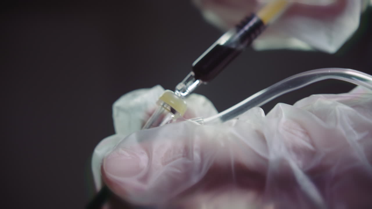Gloved hands prepare the syringe for injection