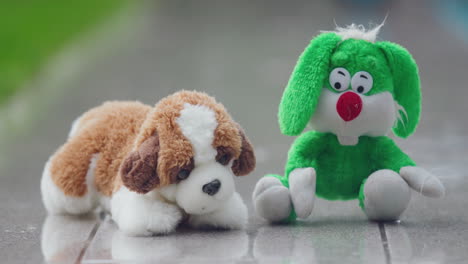 two soft toys - a hare and a puppy get wet in the rain in the backyard of the house