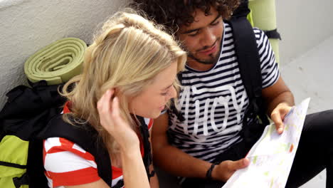 Happy-hipster-couple-looking-a-map-and-pointing-the-direction-