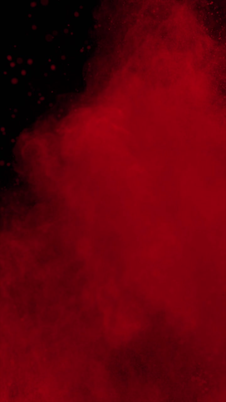 Video 4K verticale con esplosione di polvere rossa su sfondo nero