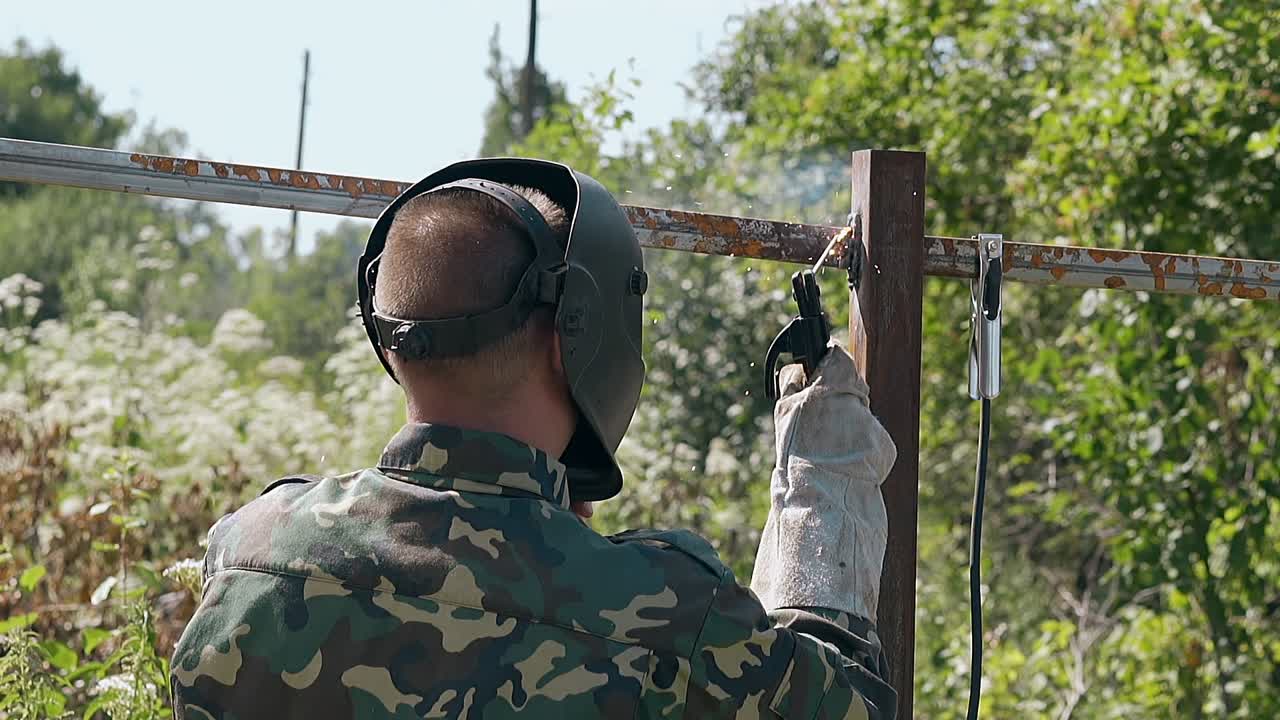 슬로우 모션 뒷면 뷰 남자가 마당에서 울타리 부품을 용접