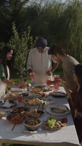 family enjoying an outdoor meal and drinks in a garden setting