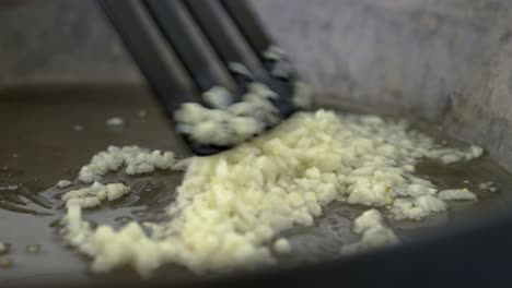 chopped garlic in a frying pan getting stirred with a spatula