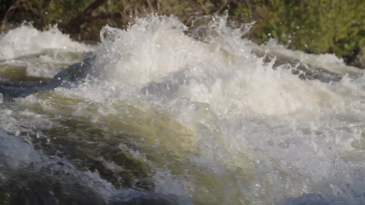 Tosende Wildwasser-Stromschnellen rauschen während der Frühjahrsschmelze in Ontario über Kalksteinfelsen. Schnell fließende Flussströmungen erzeugen starken Schaum und Nebel bei hellem Tageslicht.