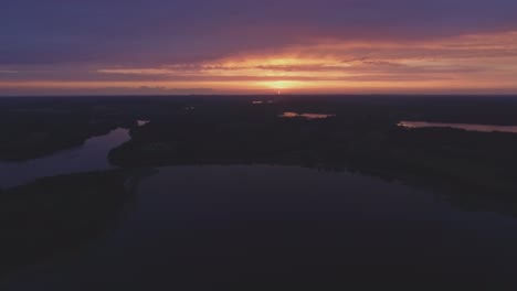 lake surrounded by forests illuminated by sunset