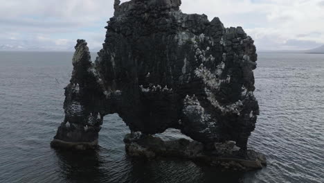vista aérea de aves volando alrededor de la roca de basalto de hvítserkur cerca de la costa de islandia, tomada por un avión no tripulado