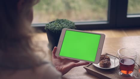 woman hands holding and touching tablet horizontal with a green screen