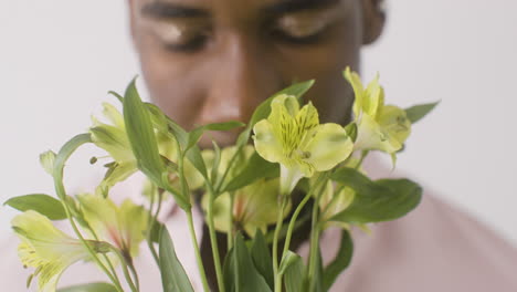 close up view of man smelling flowers and looking at front