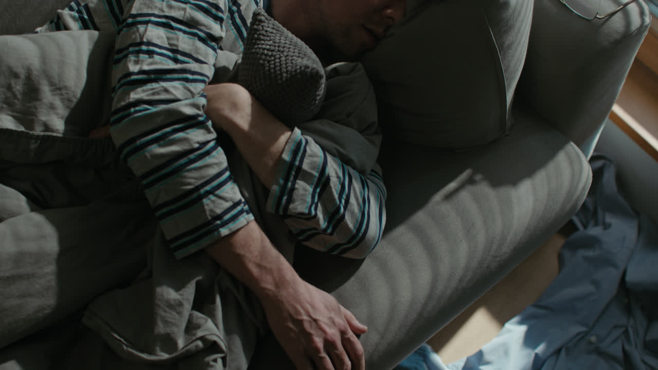 A sad man wakes up tired on his sofa