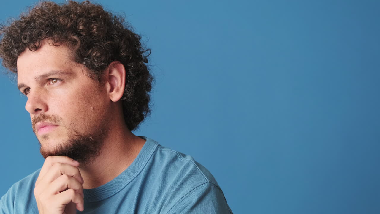 Thoughtful Young Man with Curly Hair Smiles at Camera
