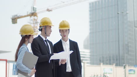 architect and inspector in helmets with documents checking plans at construction site