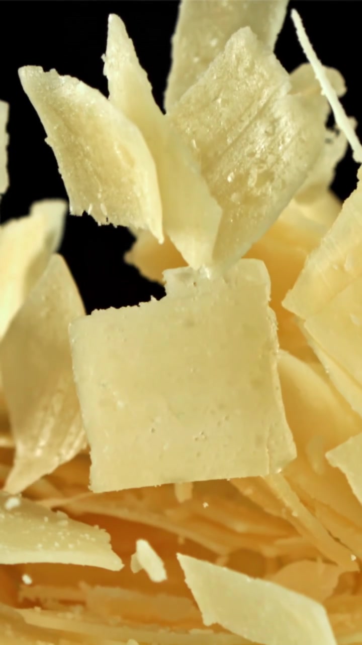 Parmesan Cheese Flakes Falling in Slow Motion on Black Background