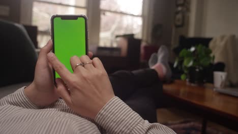 young woman swipes right on her smartphone with green screen replacement