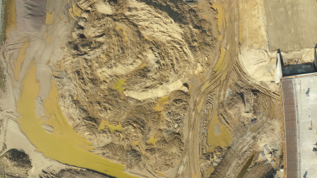 Top-down view of a construction site with excavation work and muddy terrain