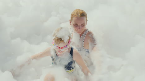 a foam party in a resort hotel on the beach a young mother with her daughter having fun in a huge am