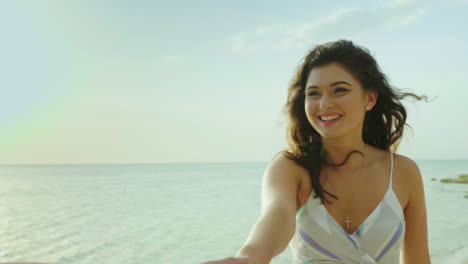 mujer joven conduce detrás de sí misma retrato va a lo largo de la playa sonrisas cabello croa en el viento pov vi