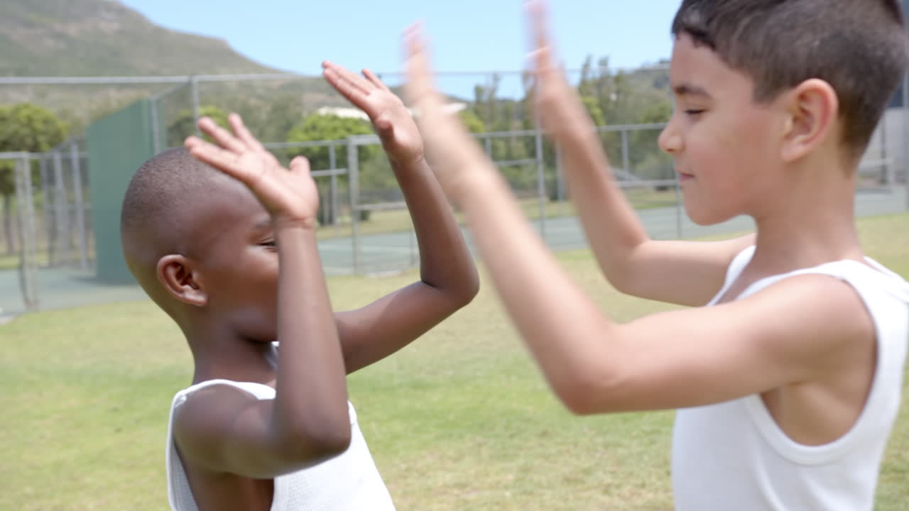 In school, children playing outside on grassy field near tennis court