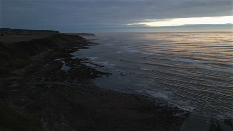 Aufnahme-Einer-Luftdrohnenaufnahme-Der-Cleveland-Way-Klippen-In-Scarborough,-Nord-Yorkshire,-An-Einem-Nebligen-Morgen-Bei-Sonnenaufgang