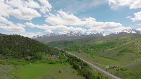 luchtbeeld van de prachtige colorado bergketen met sneeuwbedekte toppen op een zonnige, blauwe hemeldag in de zomer met groene velden, bomen en berghuizen
