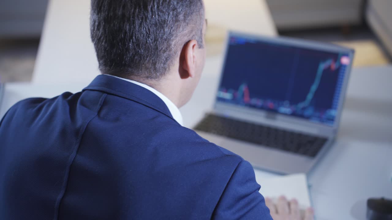 Uomo vincente in borsa felice che osserva i grafici rialzisti sul laptop.