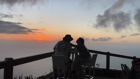 amorous young couple having dinner and enjoying kisses on the romantic view of mirador de la peña at sunset, el golfo. spain