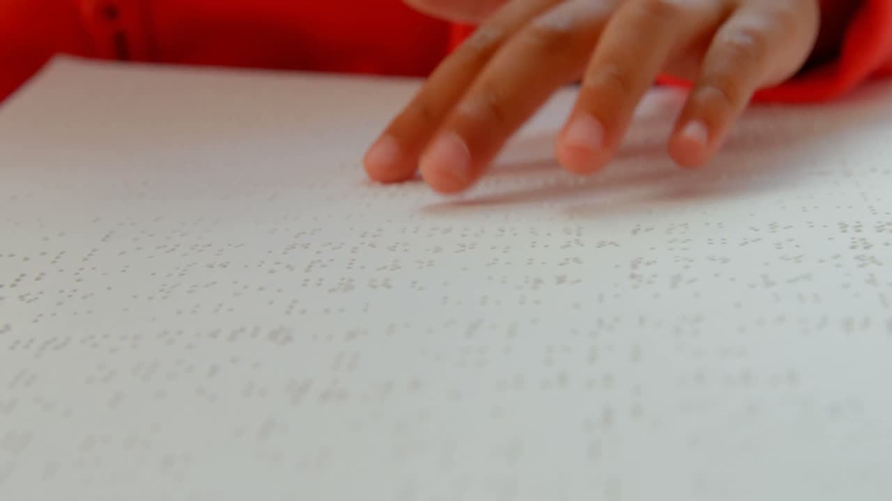 primer plano de un escolar asiático ciego leyendo un libro en braille en el aula de la escuela 4k