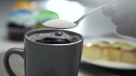 cristales de azúcar cayendo de una cucharada a una taza de café - cámara lenta