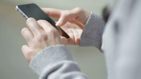 female hands typing message on smartphone outdoor.