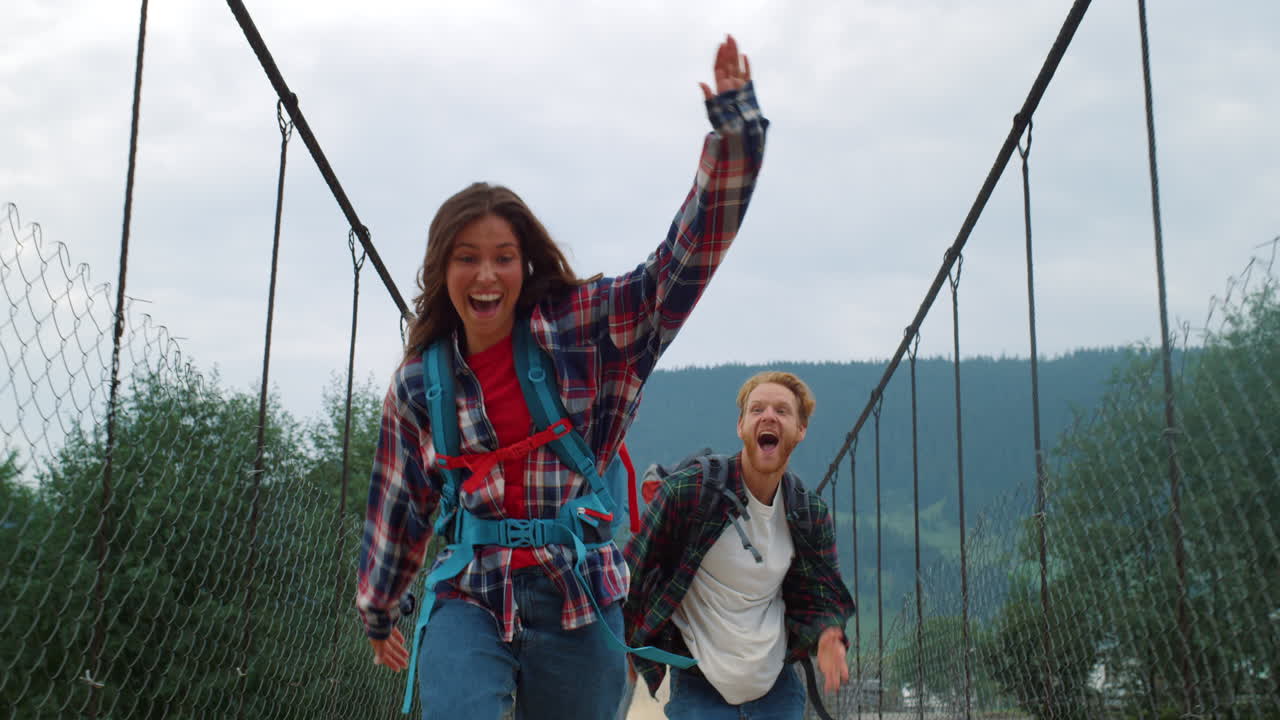 dos viajeros se divierten en el puente de las montañas. una pareja emocionada juega juntos afuera