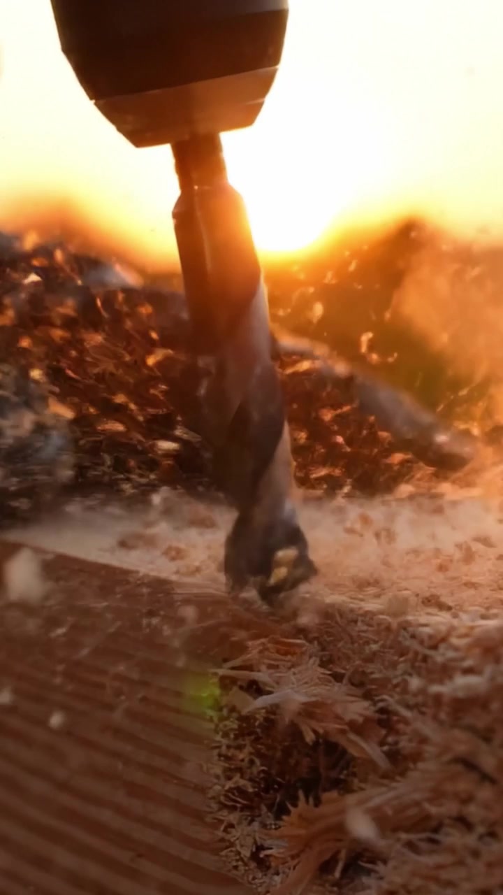 Capturando a Arte da Marcenaria: Close-Ups de uma Broca em Ação Enquanto Penetra uma Superfície de Madeira Contra um Belo Cenário de Pôr do Sol