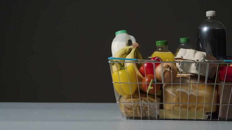 Studio Shot Of Basic Food Items In Supermarket Wire Shopping Basket With Copy Space