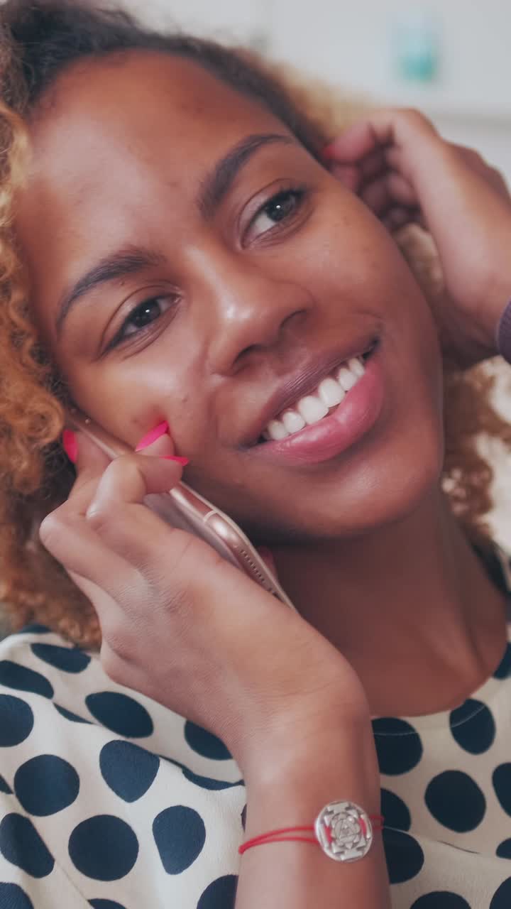 Smiling woman talks on phone in bright indoor setting