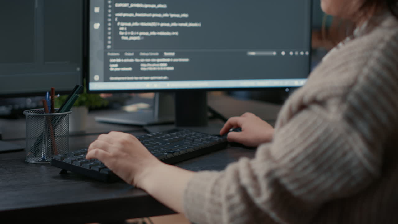 Closeup of caucasian software coder hands typing on keyboard in front of computer screen