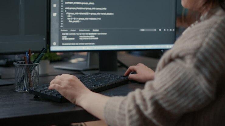 Closeup of caucasian software coder hands typing on keyboard in front of computer screen