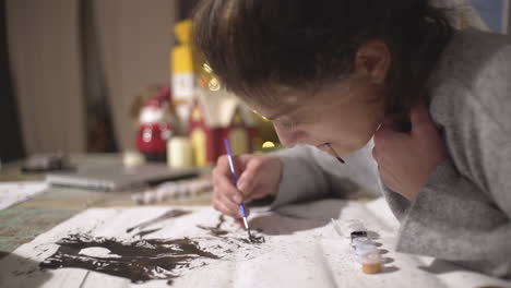 mujer caucásica pintando sobre lienzo blanco, pintando por método de números 4k, toma estática de vista lateral, fondo borroso decorado con navidad
