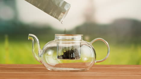 pouring loose leaf tea into a glass teapot