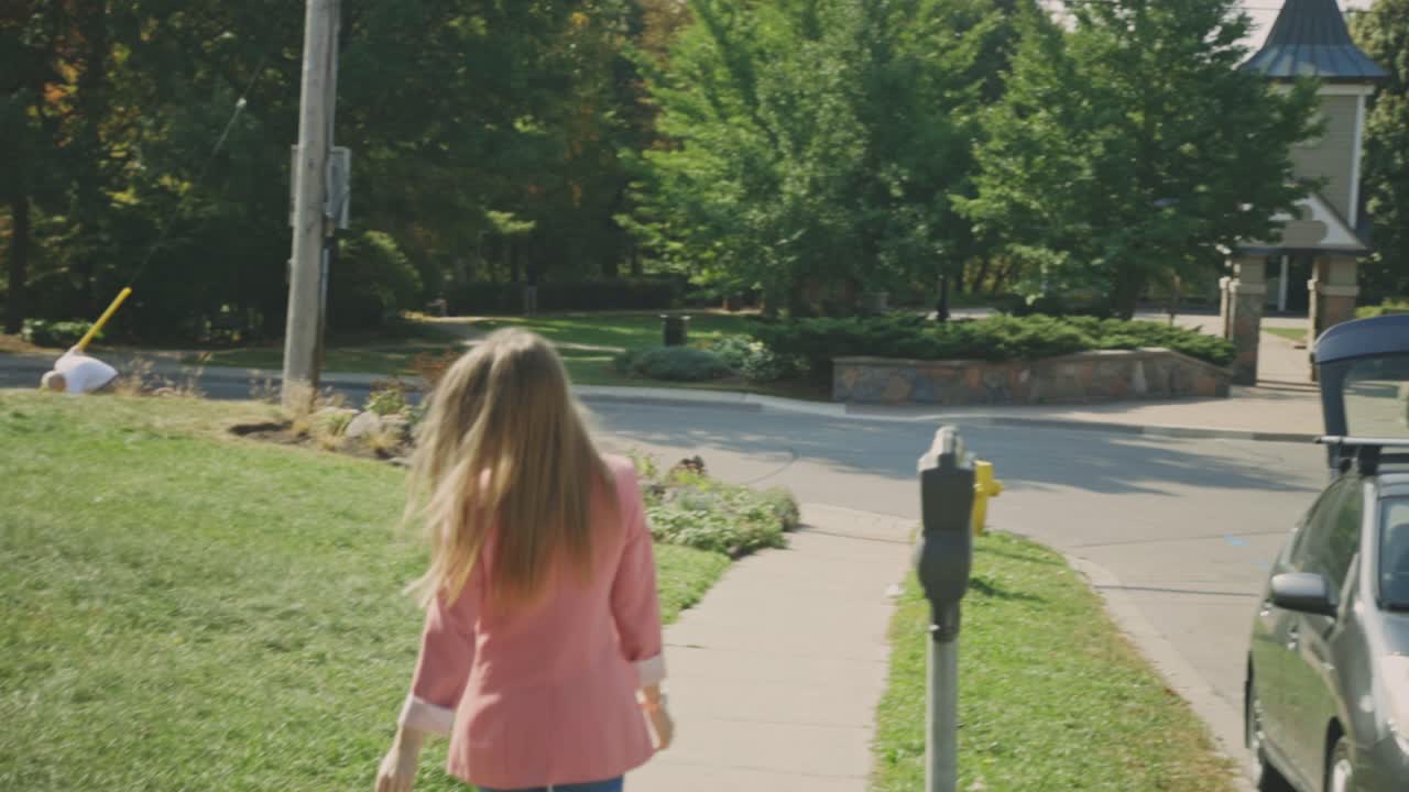 캐주얼 복장을 한 여성 모델의 뒷모습이 카메라를 통해 고개를 돌리면서 머리를 던지며 보도 위를 우아하게 걷고 있다 - 슬로우 모션