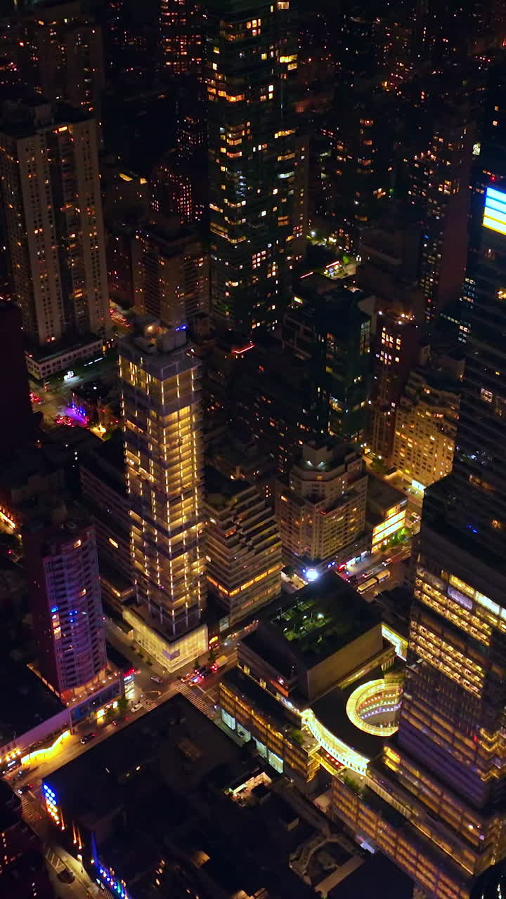 Rising high above the stunning skyscrapers of New York. Thousands of cars moving by the never sleeping city. Metropolis at night. Vertical video
