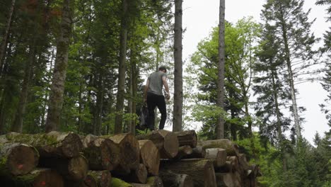 caucasian male sets out for hiking adventure as he walks on log pile in forest