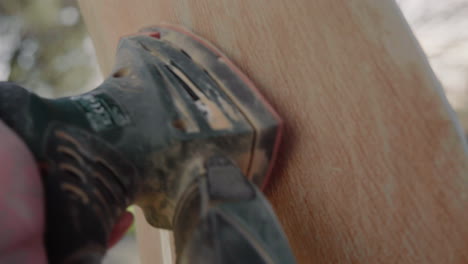 Detail-Shot-of-Handyman-Using-Polishing-Machine-To-Polish-Wood-and-refurbish-an-old-vintage-design-chair-in-the-garden-on-a-sunny-day-4K