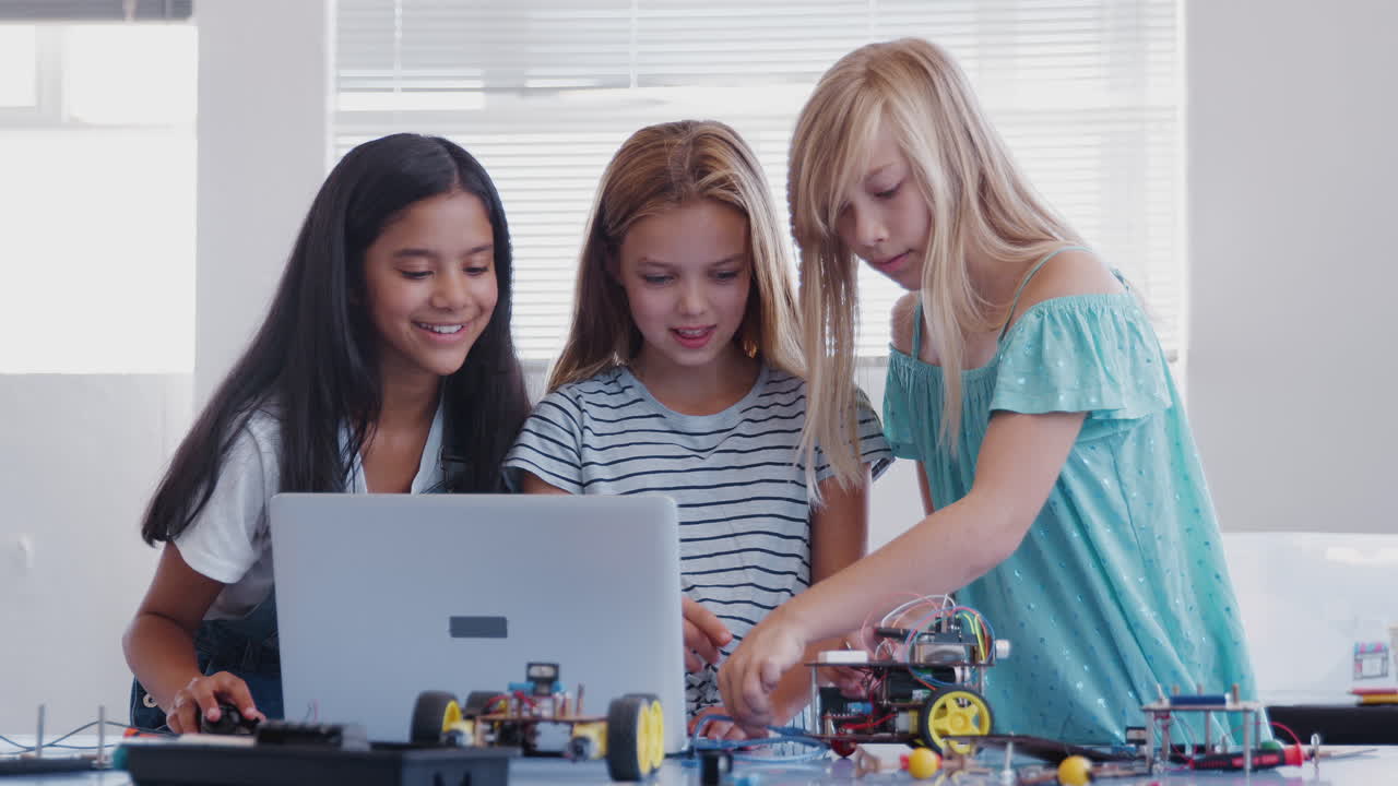 Three Female Students Building And Programing Robot Vehicle In After School Computer Coding Class