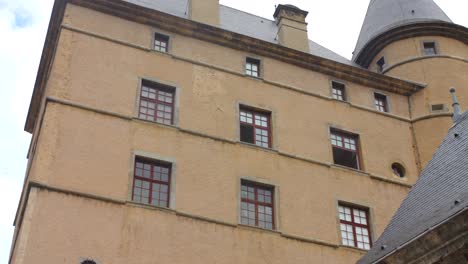 vizille castle's historic stone walls and red windows shot from below on a cloudy day