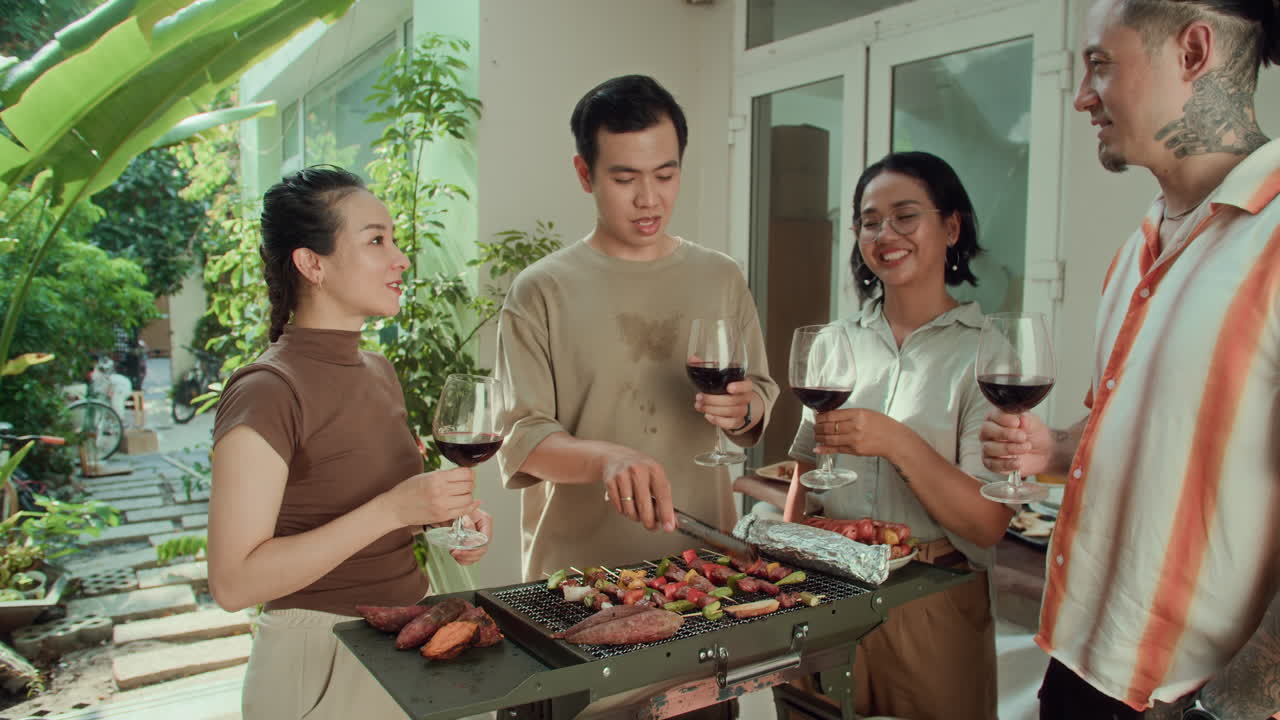 Friends Talking, Drinking and Cooking Barbecue during Party