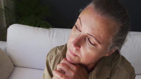 Close-up-of-caucasian-senior-woman-holding-walking-stick-while-sitting-on-the-couch-at-home