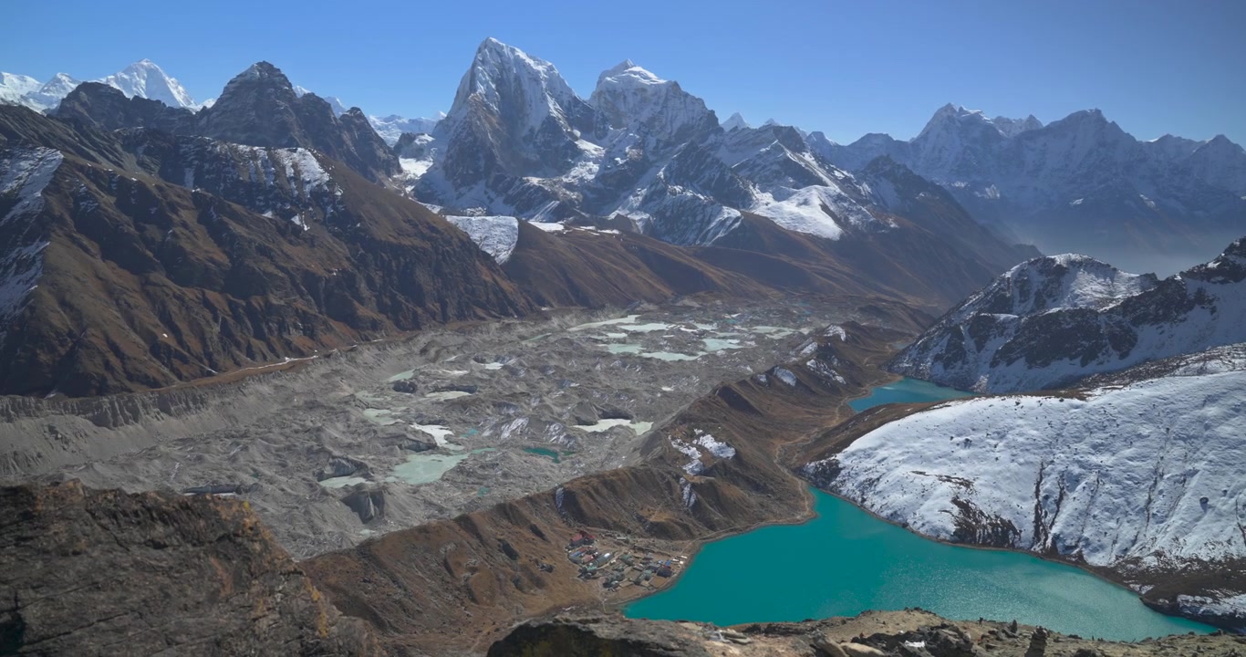 Gokyo Ri Everest region Nepal, camera pans across the high altitude landscape revealing turquoise lakes, Ngozumpa Glacier, and snow-capped Himalayan mountains.