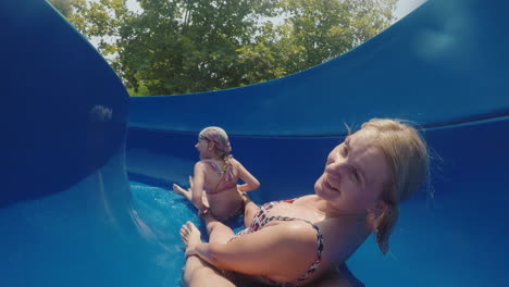 A-Happy-Family-With-A-Child-Is-Riding-A-Water-Slide-Laughing-Waving-Their-Hands-At-The-Camera-Slow-M