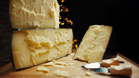 medium hard cheese head parmesan on wooden board, with cheese parmesan knifes. slide shot